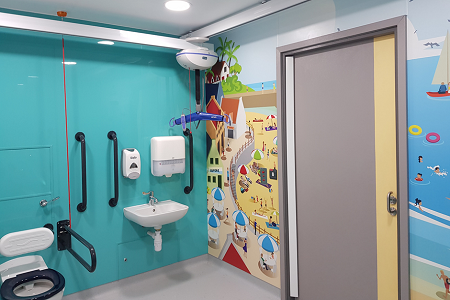 Children supported by beach-themed inclusive washroom 